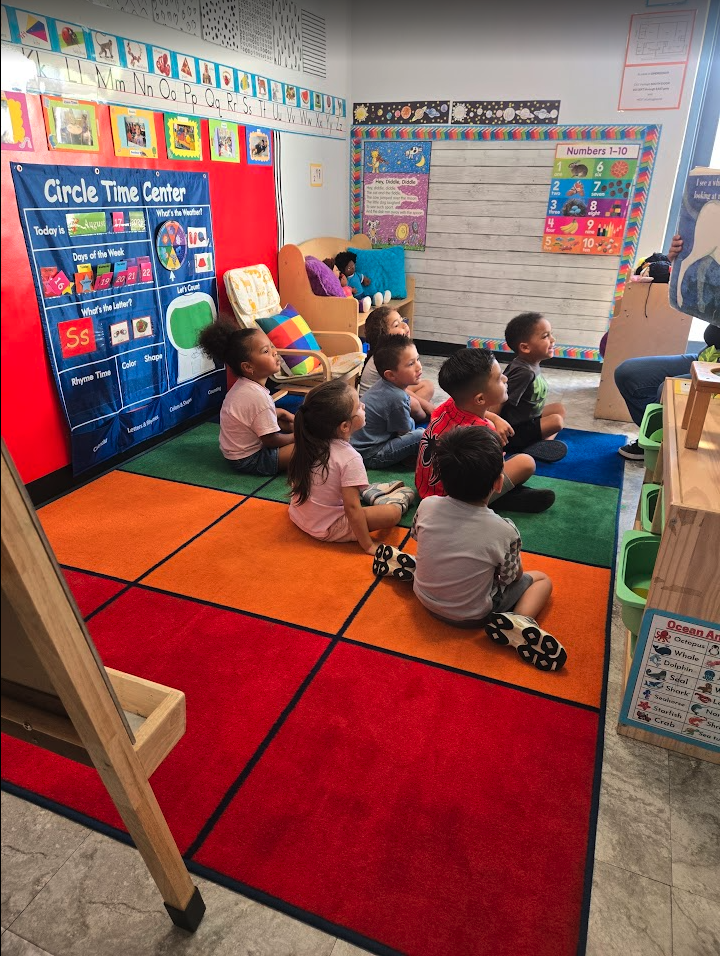 Preschoolers gathered on a colorful rug at the Circle Time Center