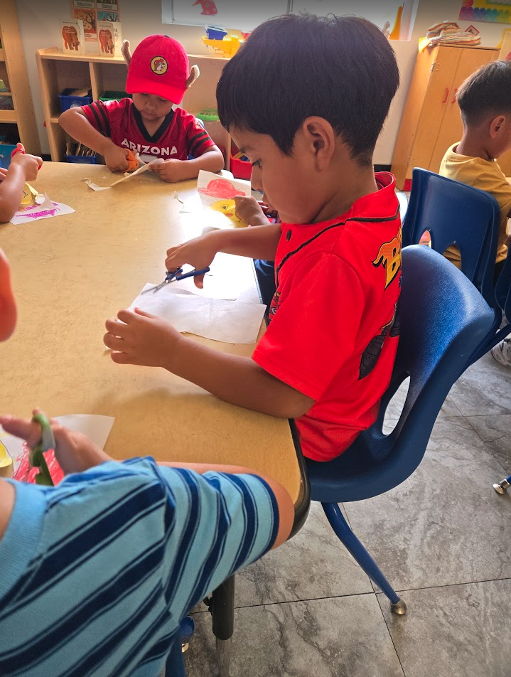 Children practicing cutting and craft skills at a table