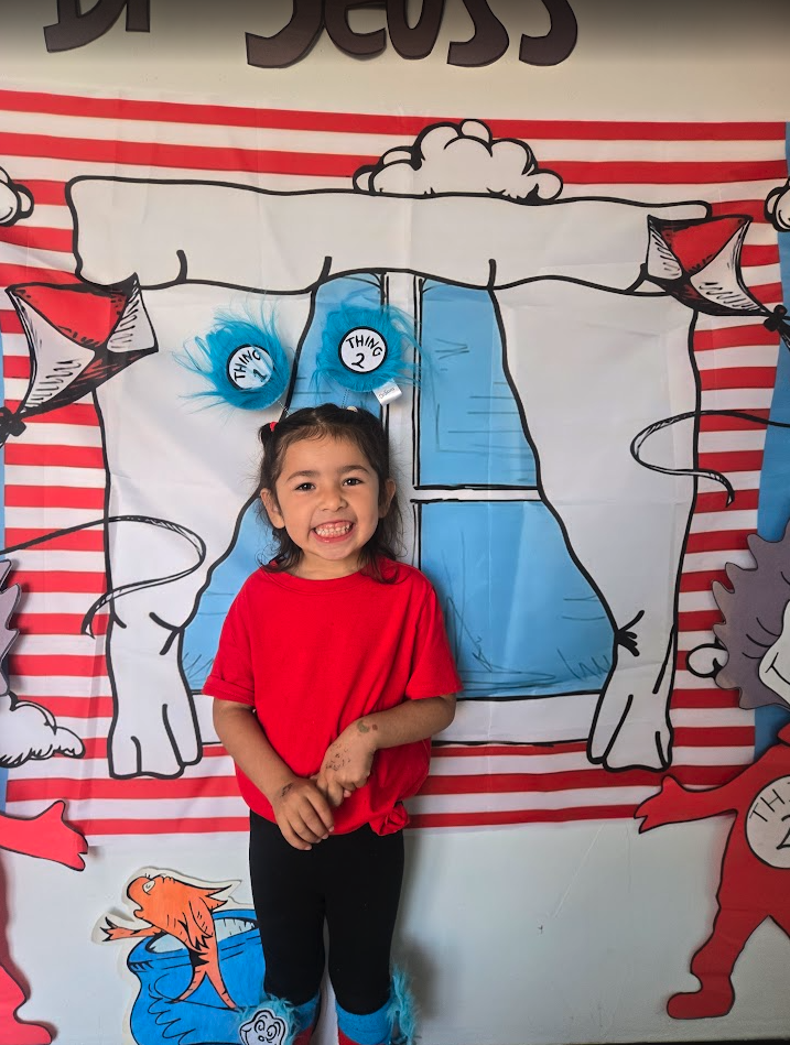 A child posing in front of a Dr. Seuss themed backdrop