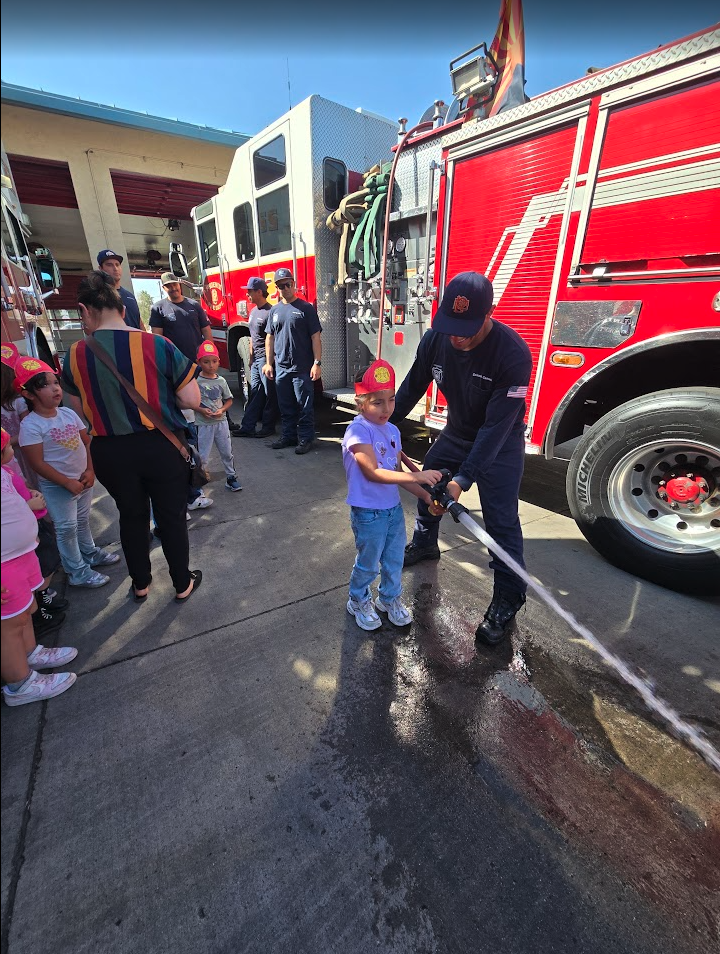 A child using a fire hose during a firefighter field trip