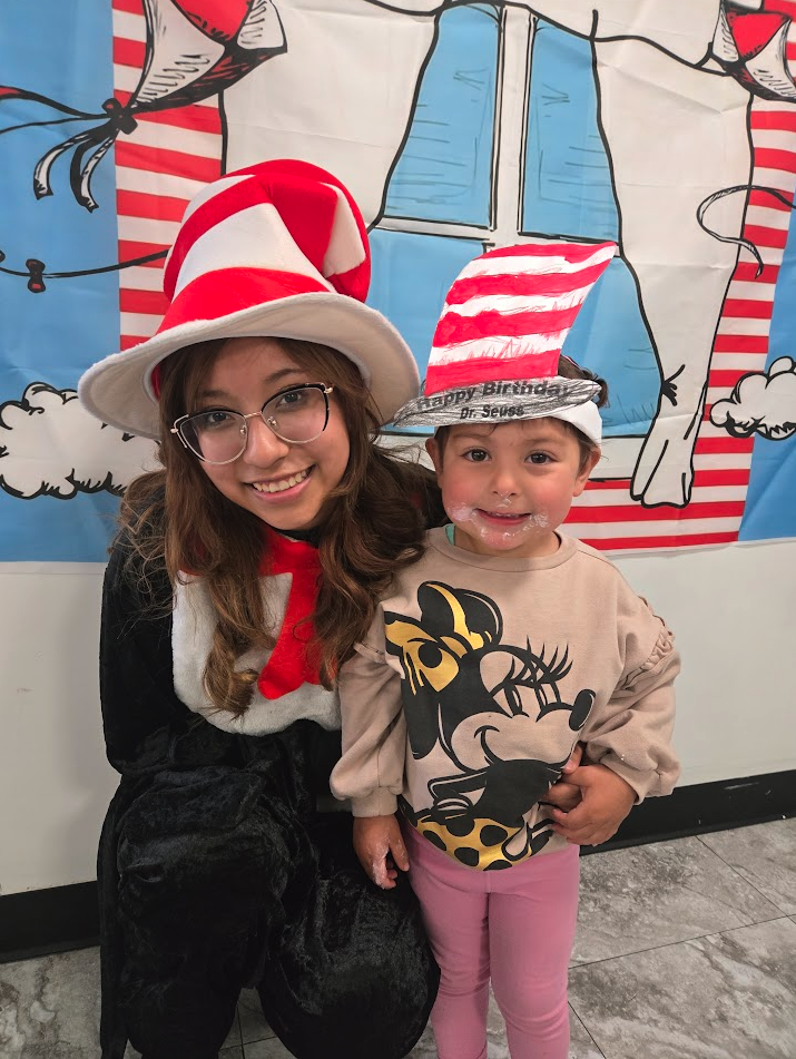 A teacher dressed as the Cat in the Hat with a child on Dr. Seuss day