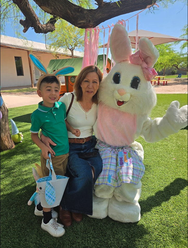 A boy and grandparent posing with the Easter Bunny at the spring party