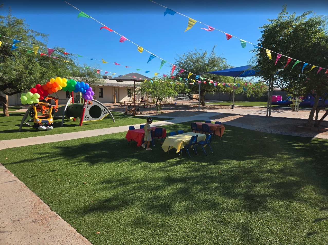 Playground decorated with a rainbow balloon arch and papel picado banners