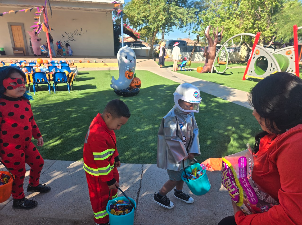 Costumed children trick-or-treating with candy buckets on the playground