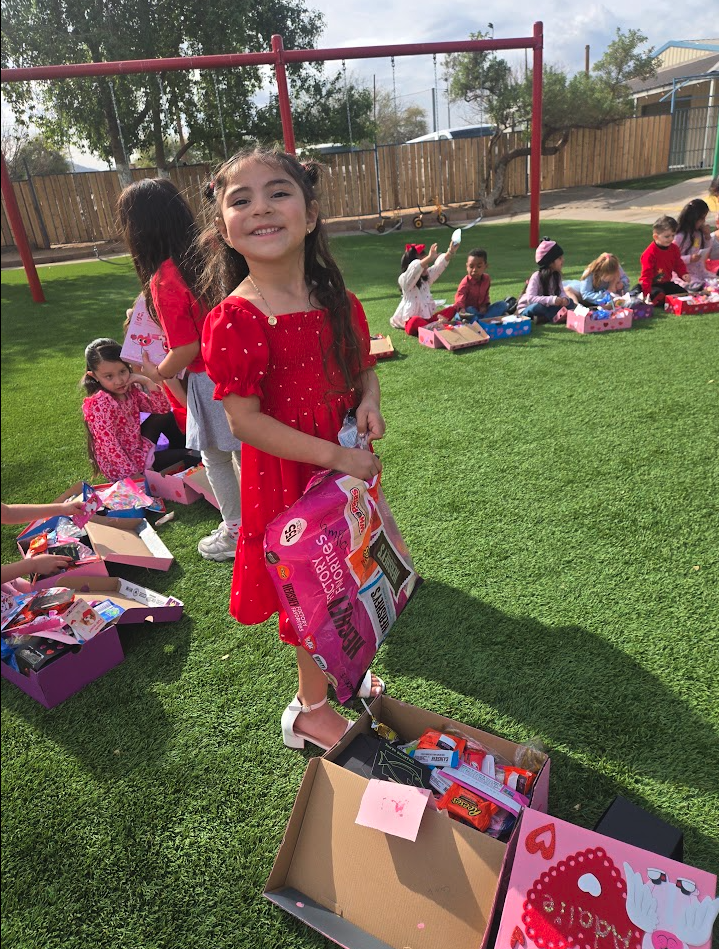 A girl in a red dress holding treats during the Valentine's Day box exchange