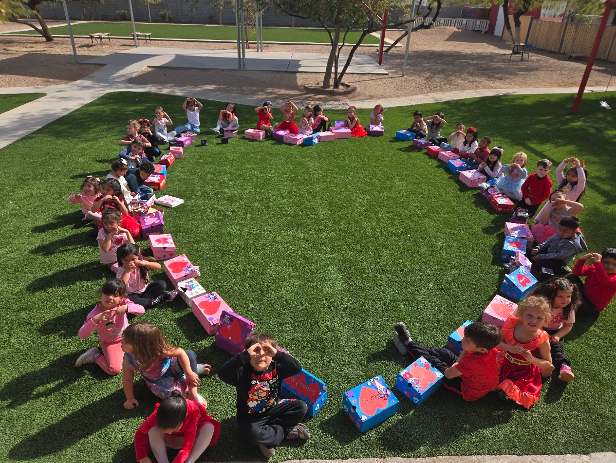 Children sitting in a heart shape with their decorated Valentine's boxes