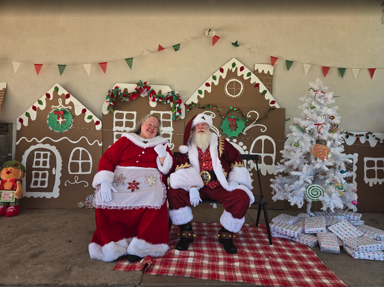 Santa and Mrs. Claus in front of a gingerbread house backdrop